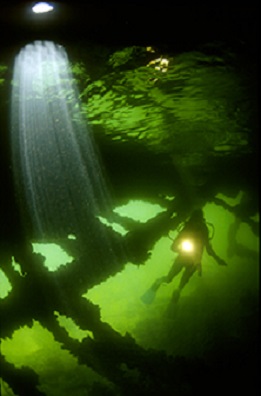 Decorative image of diver underwater with light. 