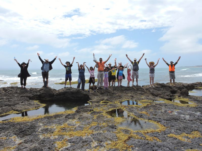 A group of people throwing their arms in the air at the beach