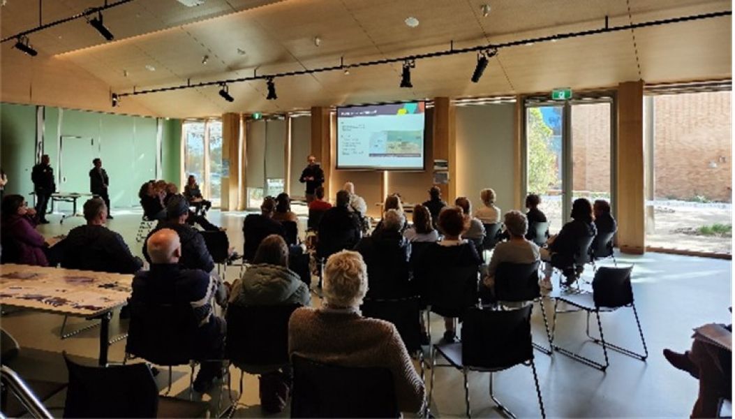 A group of people in a room watching a presentation.
