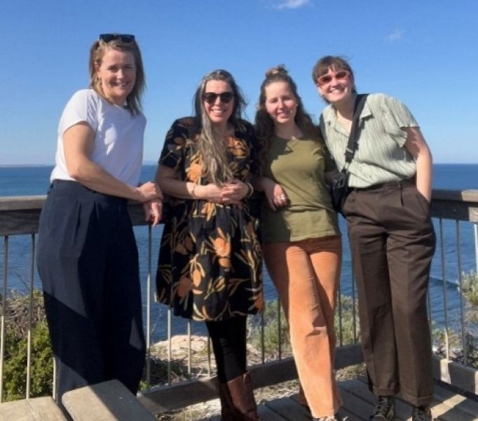 Four people standing at an ocean lookout smiling at the camera