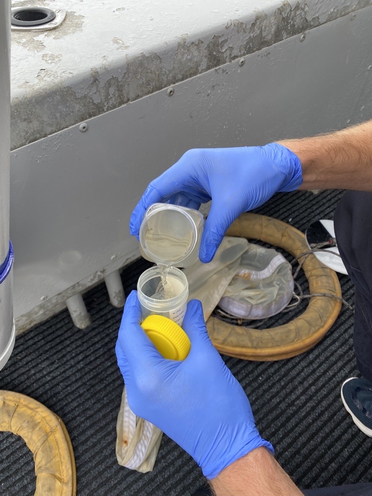 Image of hands pouring a water sample on a boat.