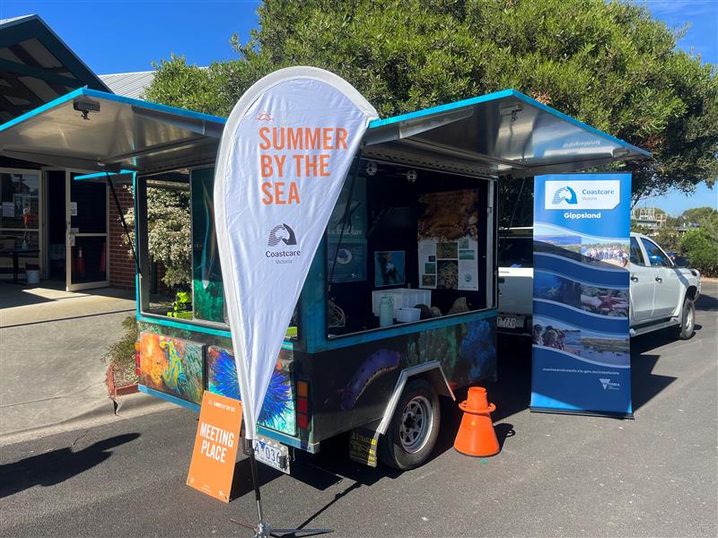 A trailer with a 'Summer by the Sea' sign and posters.