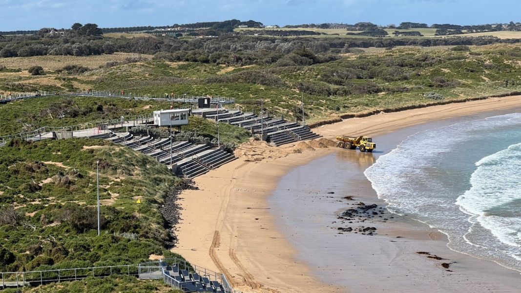 A beach with a body of water and viewing stands overlooking the beach. 