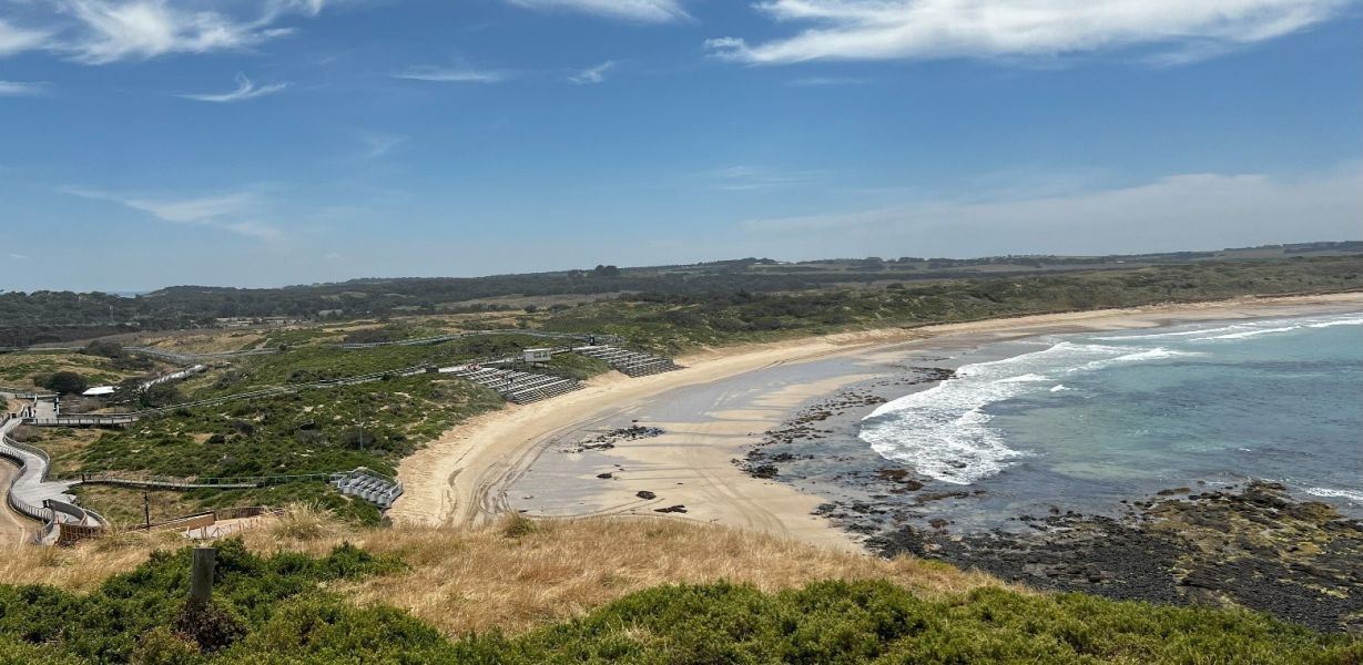 A beach with a body of water and viewing stands overlooking the beach. 