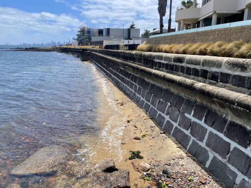 A stone wall next to a body of water.
