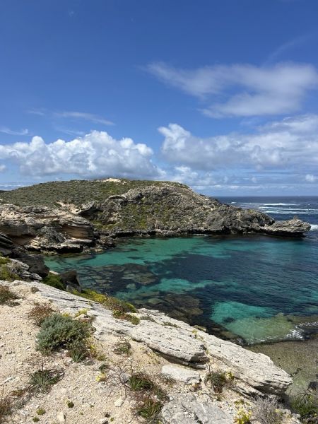 A rocky beach with blue water and blue sky.